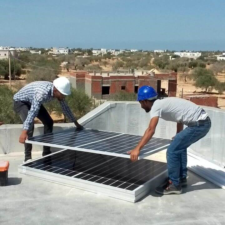 Technicien installant des panneaux solaires sur un toit en Tunisie pour une énergie propre et durable